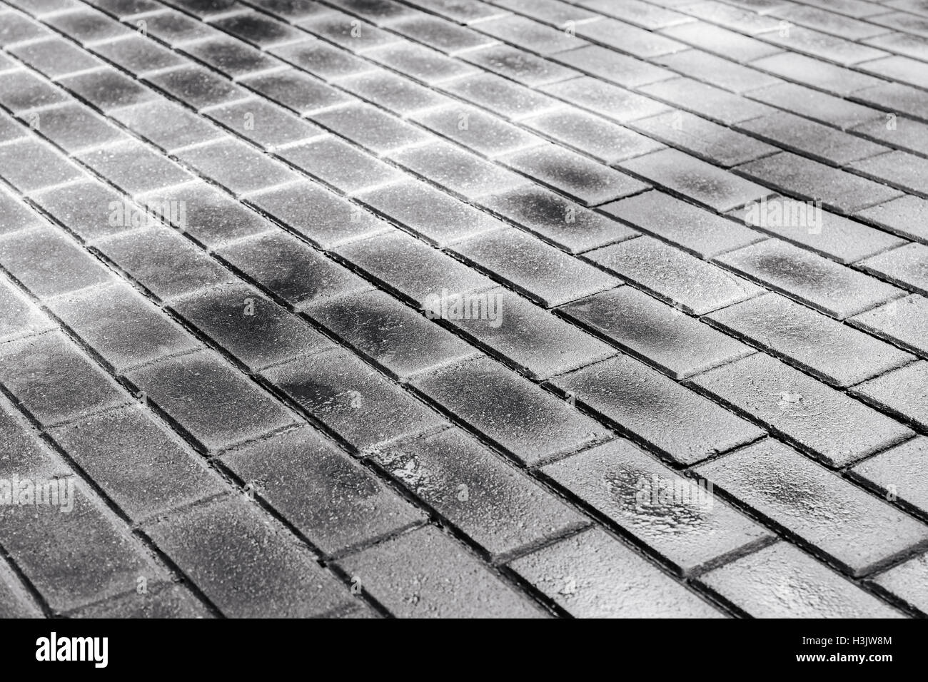 Raggi di sole gettare luce sul grigio scuro marciapiede essiccamento dopo la pioggia Foto Stock