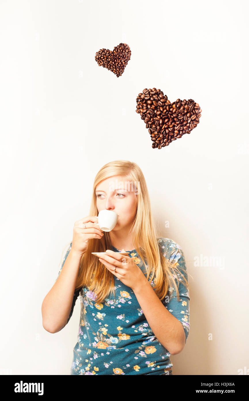 Bionda ragazza adolescente a bere caffè e a forma di cuore ad caffè sopra il suo amore per il concetto di caffè Foto Stock