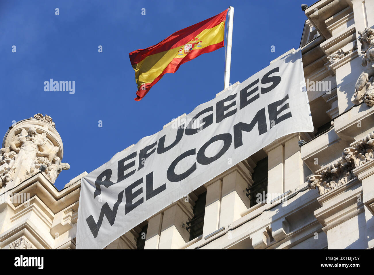 Un banner accogliendo i rifugiati pende dal Cibele Palace Madrid municipio della città sulla Plaza de Cibeles, Madrid, Spagna Foto Stock