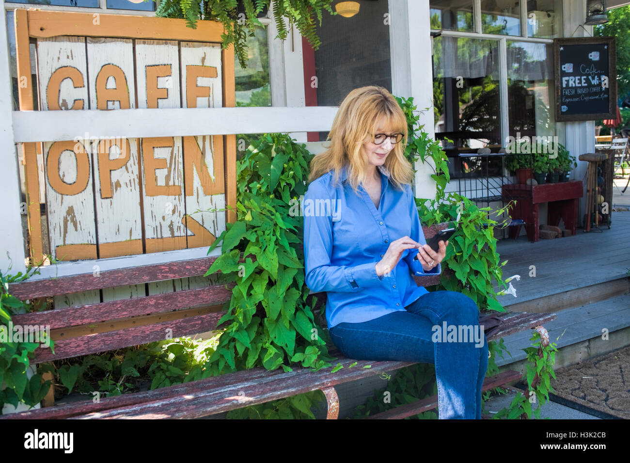 Donna che utilizza il cellulare sul banco cafe Foto Stock