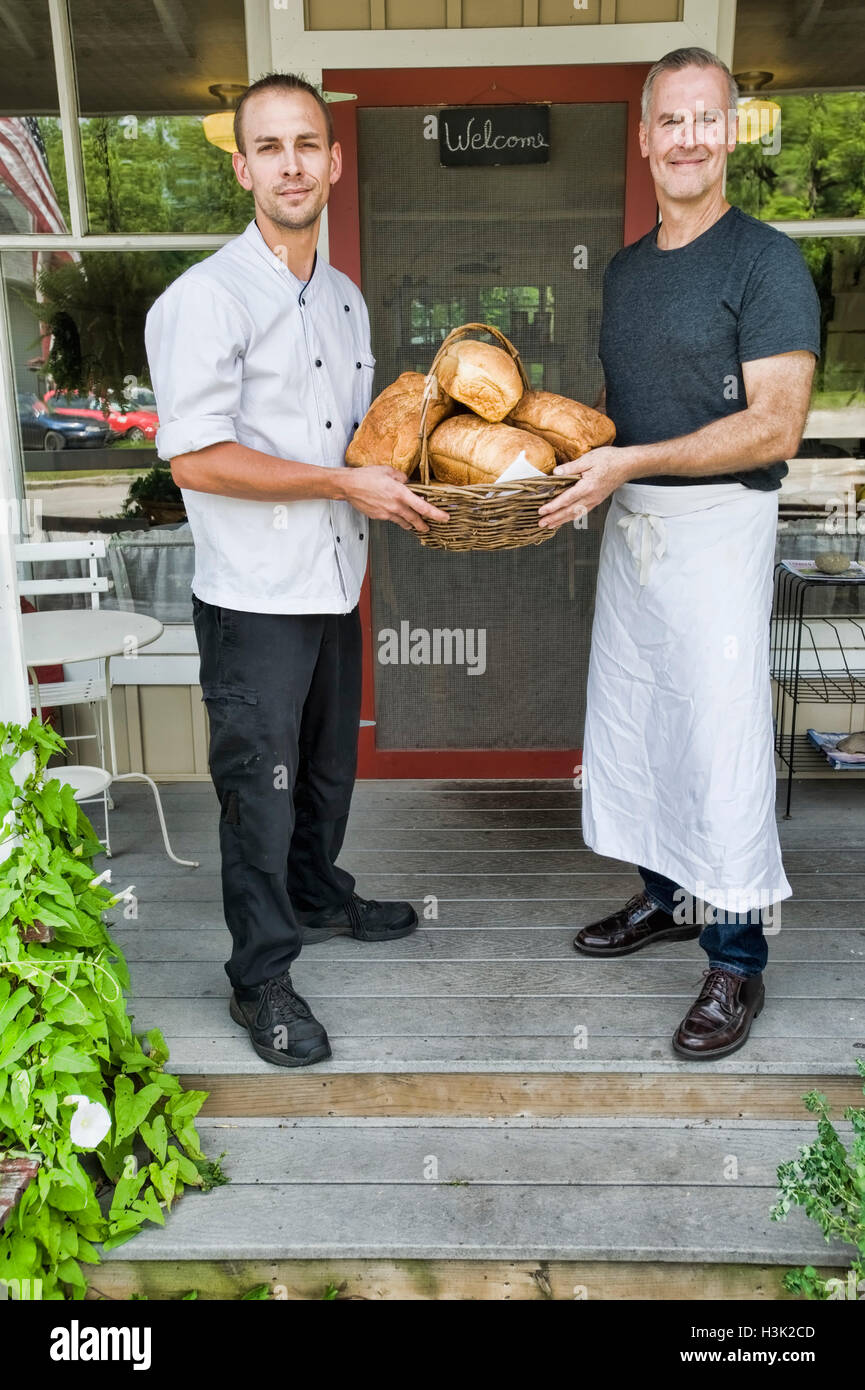 Cafe proprietario e chef con cestino del pane nella parte anteriore del ristorante Foto Stock