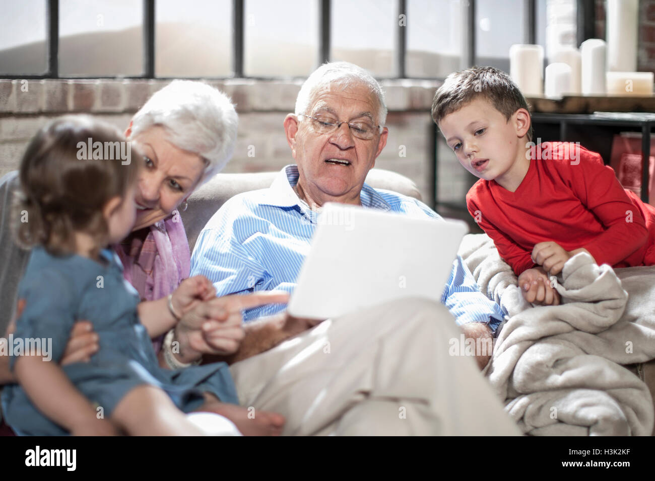Nonni a giocare con i nipoti, utilizzando tavoletta digitale in casa Foto Stock