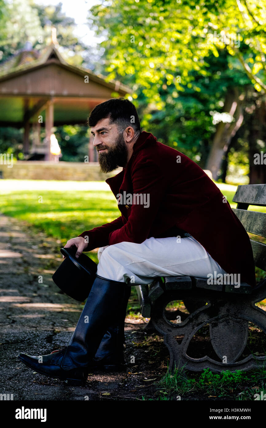 Regency vestito uomo seduto su una panchina nel parco Foto Stock