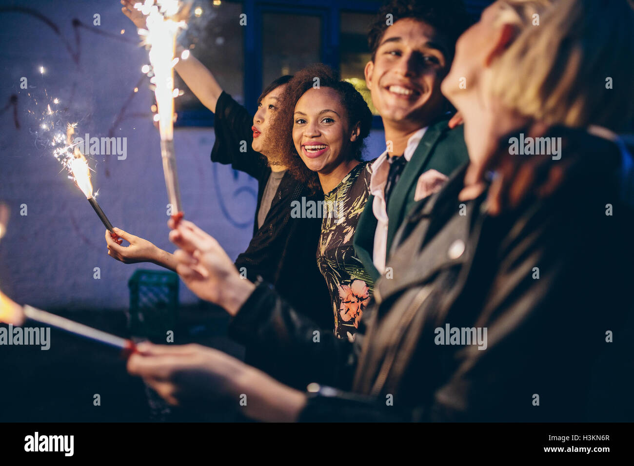 Gruppo di amici godendo con botti. Giovani uomini e donne godendo il veglione di Capodanno con fuochi d'artificio. Foto Stock