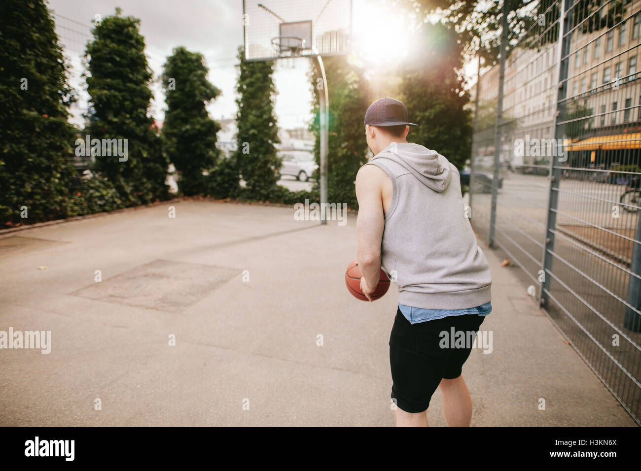 Vista posteriore del colpo di streetball giocatore giocare a basket. Giovane ragazzo giocare a basket sul tribunale aperto. Foto Stock