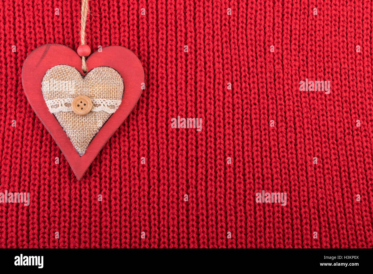 Natale decorazioni in legno cuore rosso su tessuto di lana. Natale sfondo rustico con copia spazio. Foto Stock