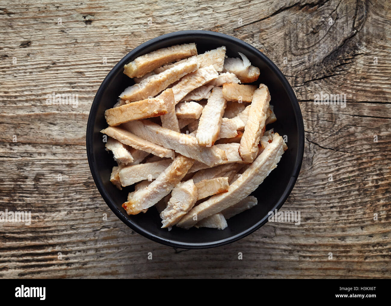 Ciotola nero di carne di maiale alla griglia le fette su un tavolo di legno, vista dall'alto Foto Stock