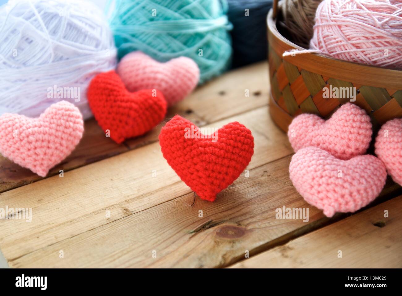 Crochet di cuore sulla tavola di legno e la sfera di sfondo del filato Foto Stock