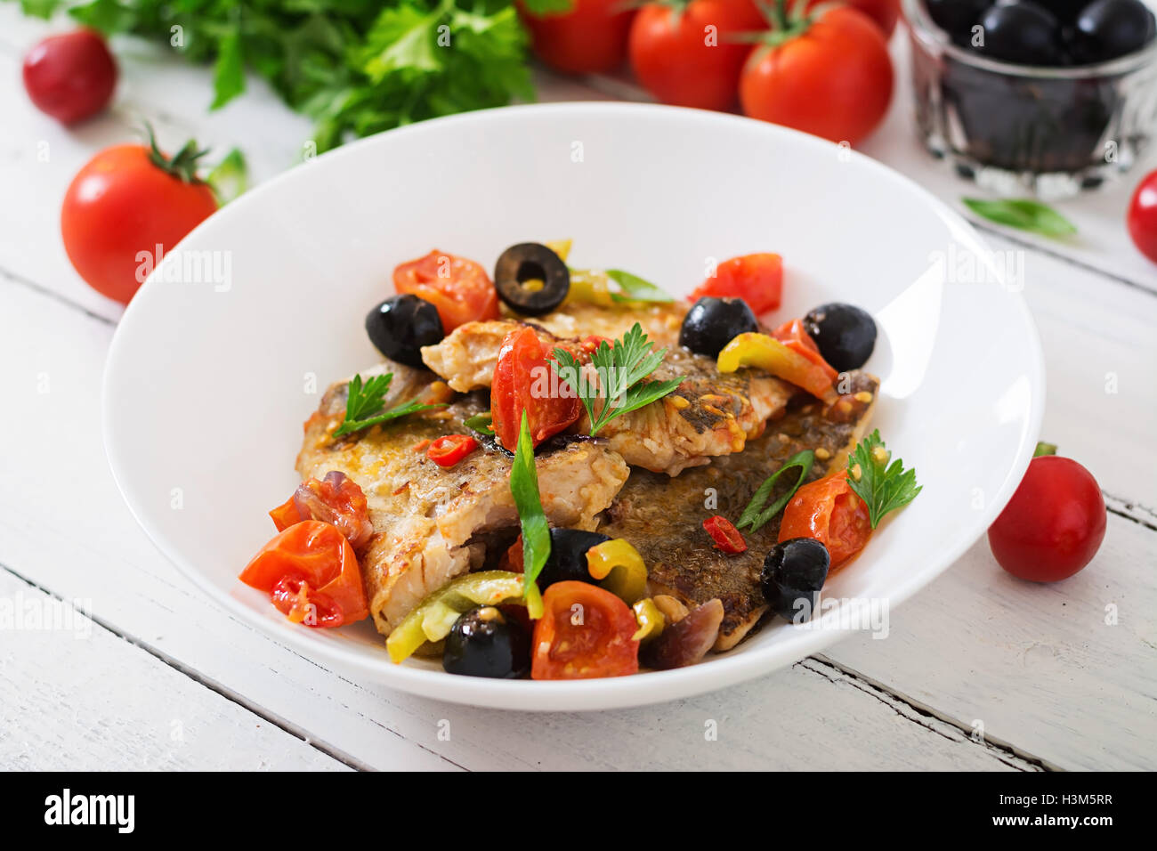 Nasello fritto di filetto con pomodoro e olive in stile mediterraneo Foto Stock