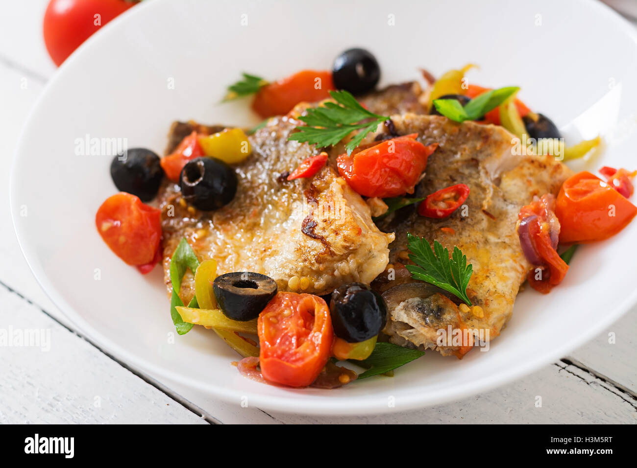 Nasello fritto di filetto con pomodoro e olive in stile mediterraneo Foto Stock