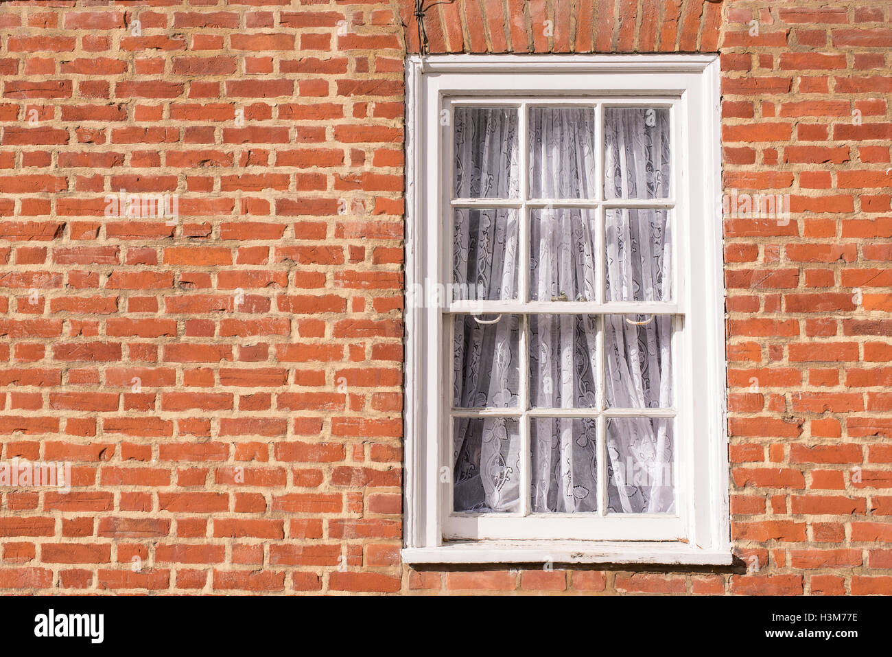 Vittoriano telaio in legno bianco finestra ad anta con pannelli di vetro su un rosso classico muro di mattoni Foto Stock