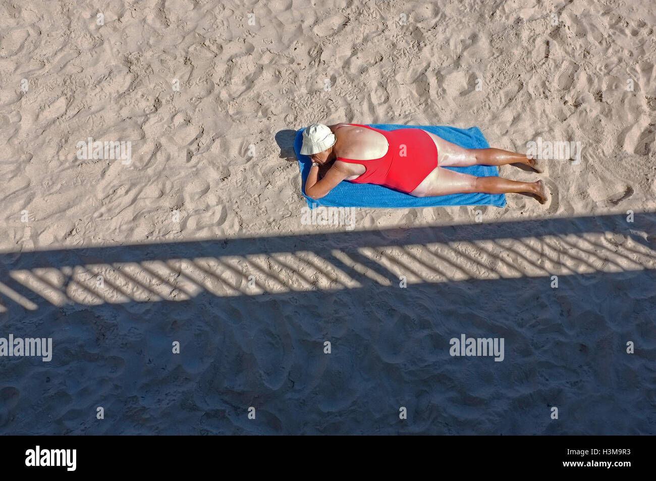 Un pensionato donna sunbathes su una spiaggia Foto Stock