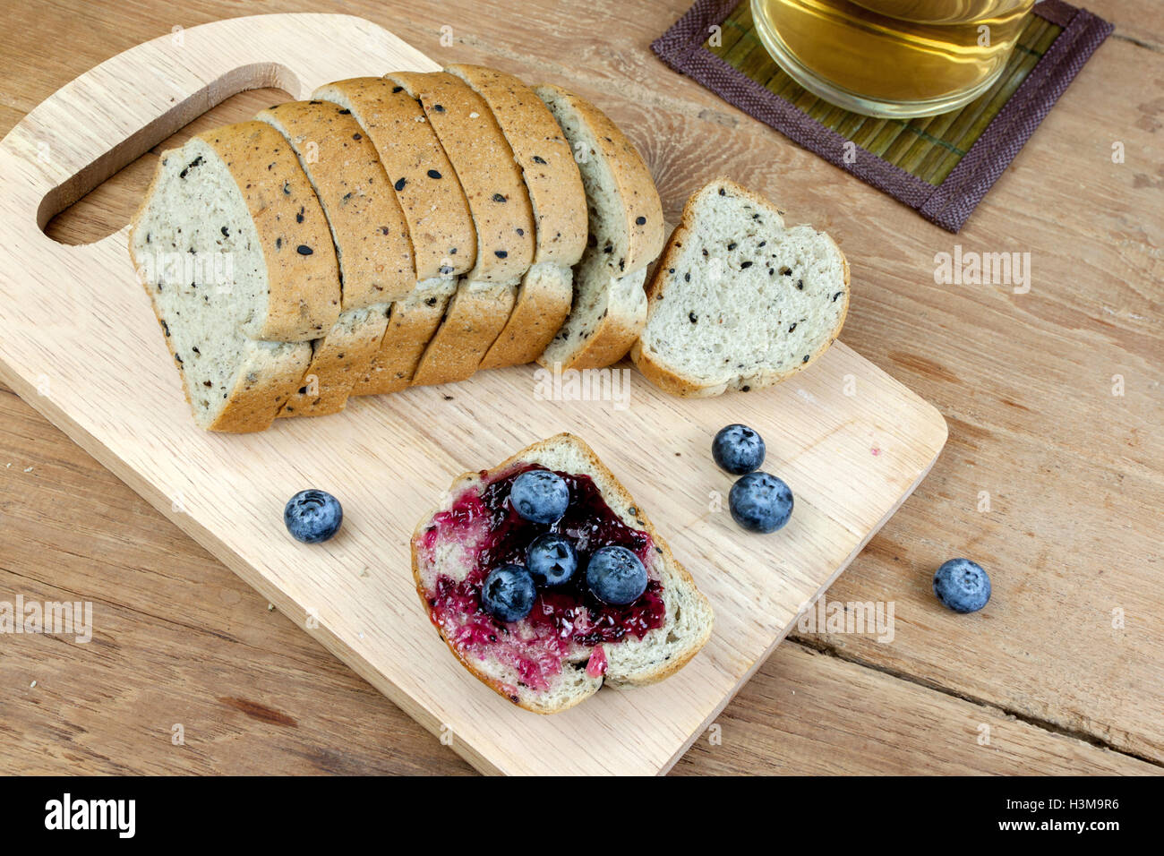 Vegetariano sesamo nero pane topping mirtillo marmellata di ribes e mirtilli freschi sulla tavola di legno Foto Stock