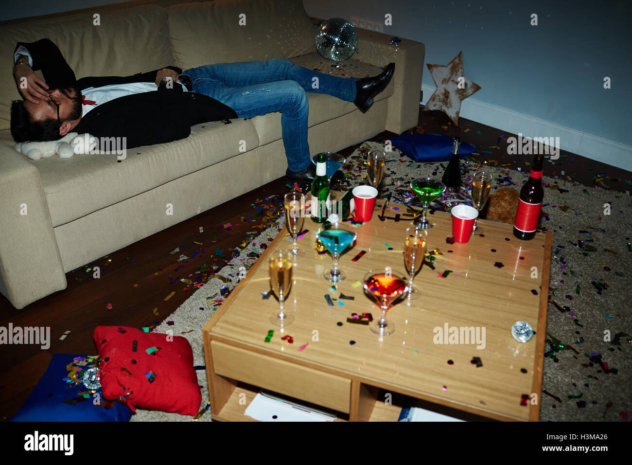 Esaurito l'uomo sdraiato sul divano dopo faticose party Foto Stock