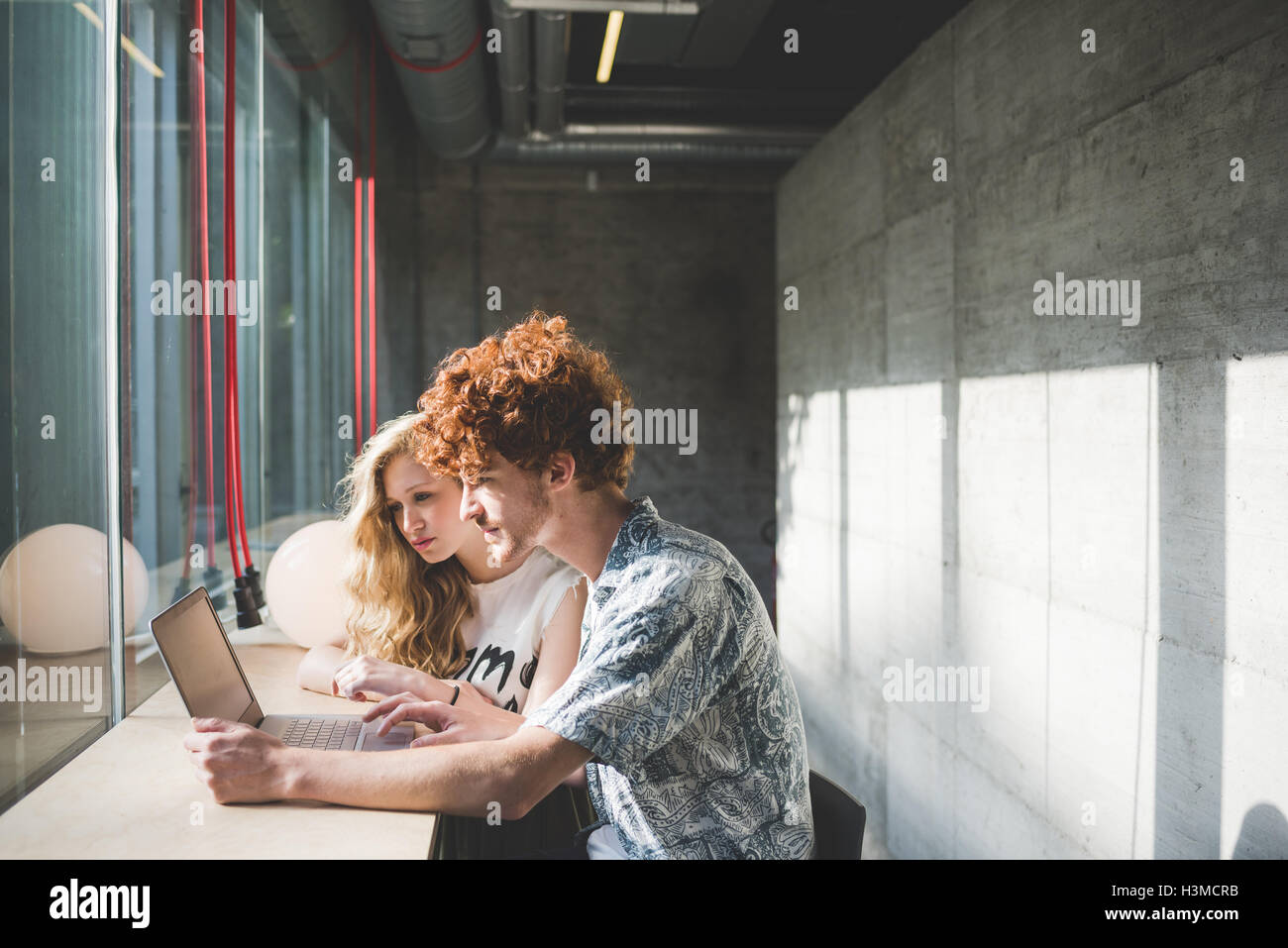 Co-lavoratori che operano su laptop accanto al banco bar dalla finestra Foto Stock