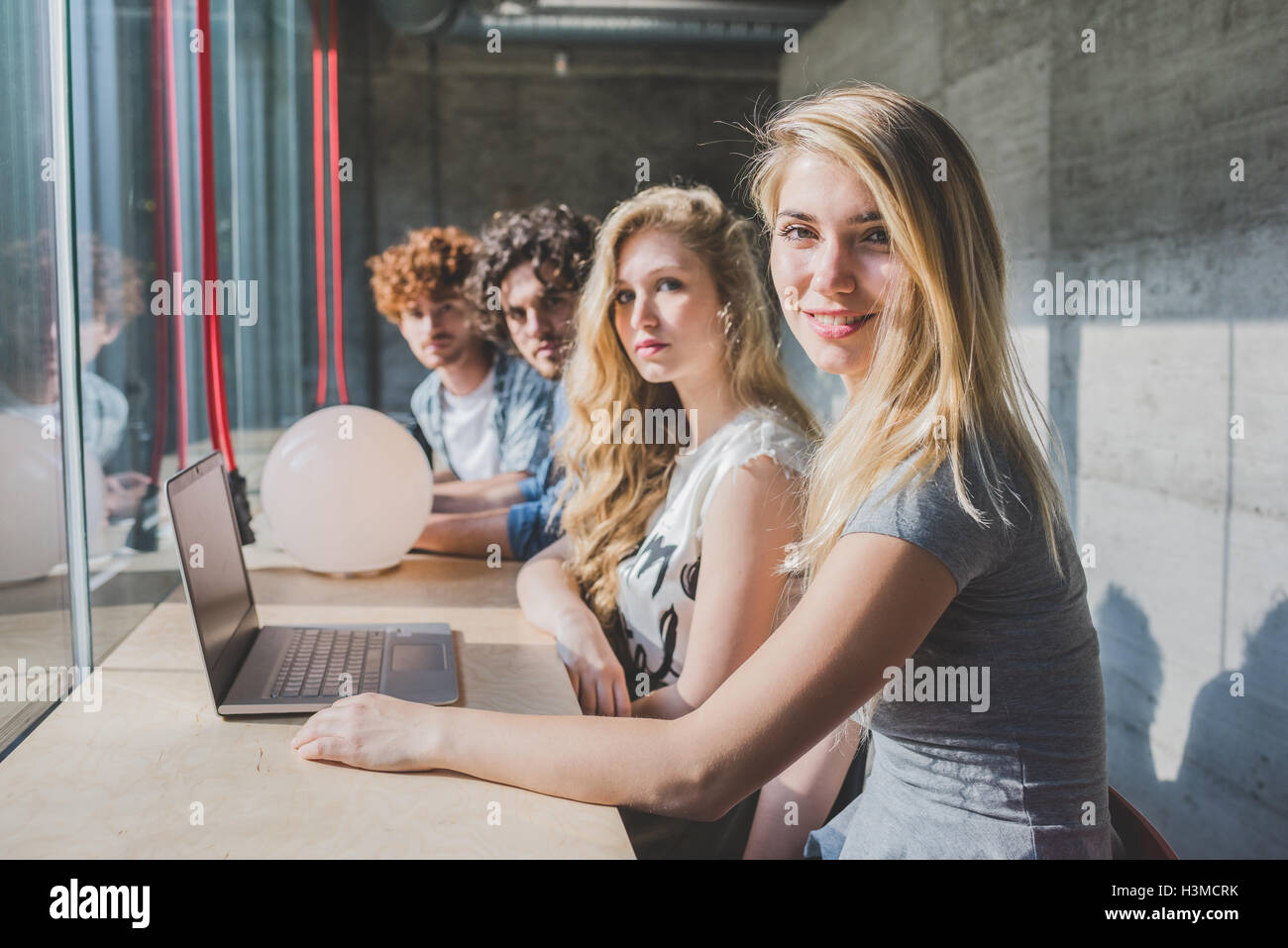 Co-lavoratori che operano su laptop accanto al banco bar dalla finestra Foto Stock
