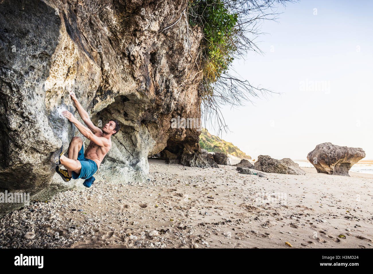 Voce maschile free climber arrampicata roccia su Pandawa Beach, Bali, Indonesia Foto Stock