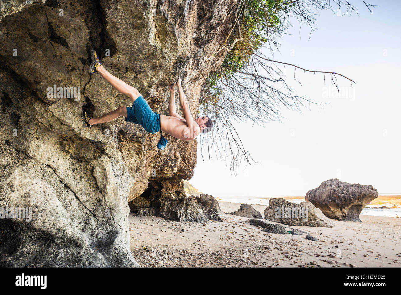 Voce maschile free climber rock climbing sporgenza su Pandawa Beach, Bali, Indonesia Foto Stock