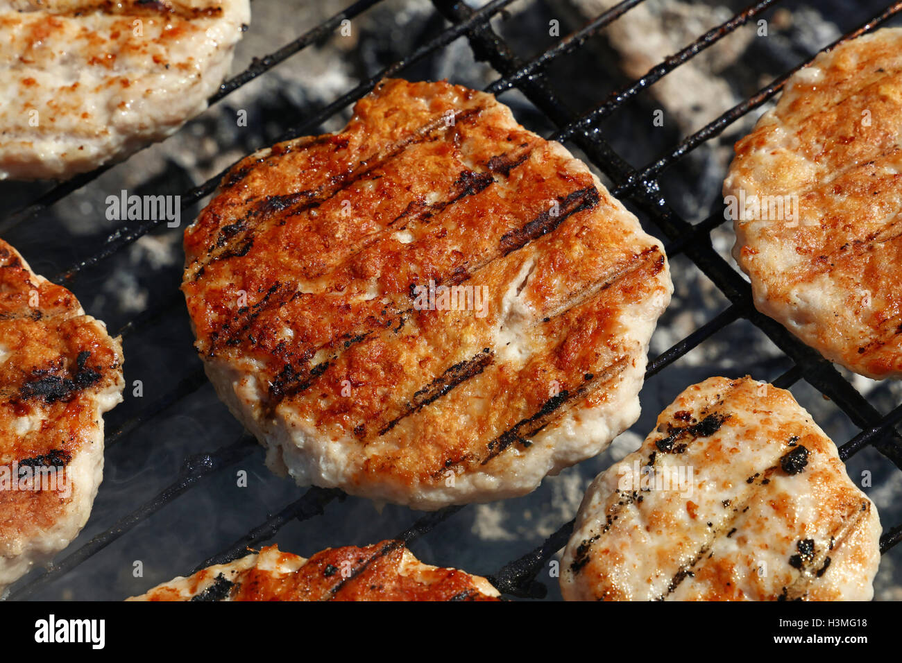 Pollo o tacchino carne di pollame barbecue hamburger grigliati per hamburger preparati sul fumo barbecue grill, close up Foto Stock