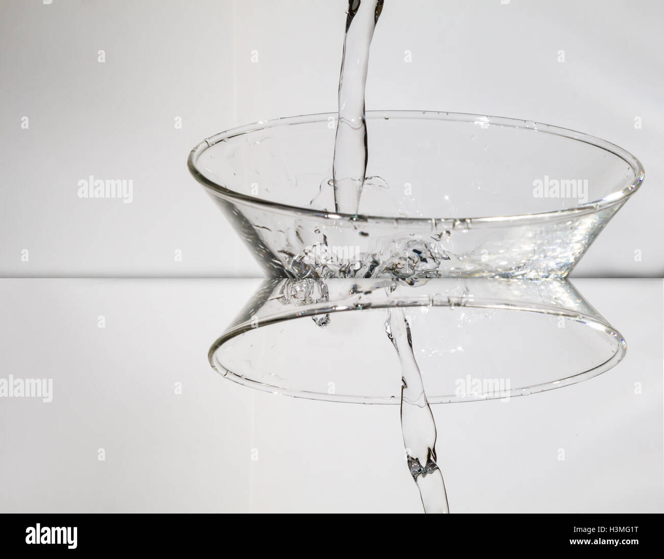 Spruzzi di acqua dal vetro isolato su sfondo bianco. Immagine manipolata Foto Stock