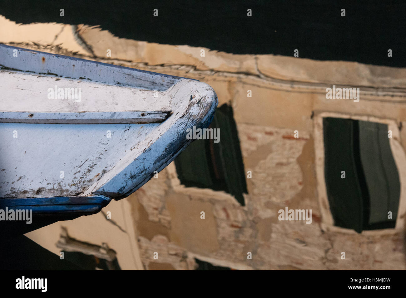 La prua di una barca in un canale con riflessioni a Venezia Foto Stock
