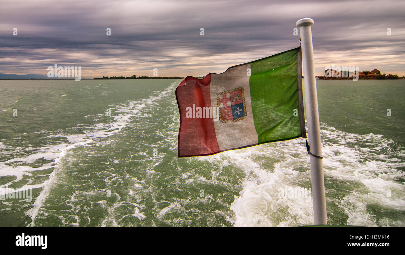 Vista sulla laguna di Venezia da una barca con la bandiera italiana Foto Stock