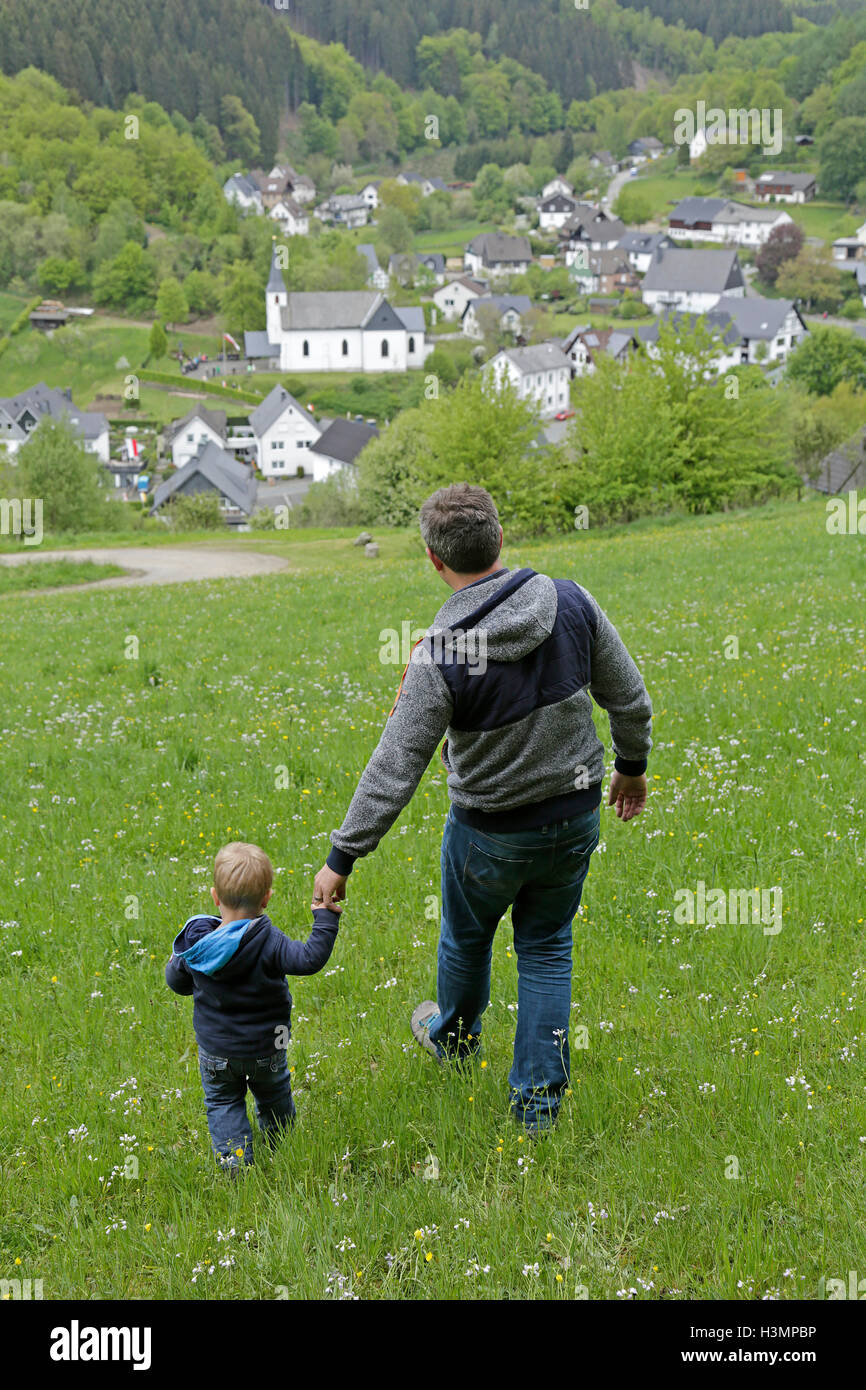 Il padre e il suo piccolo figlio a piedi attraverso un prato Foto Stock