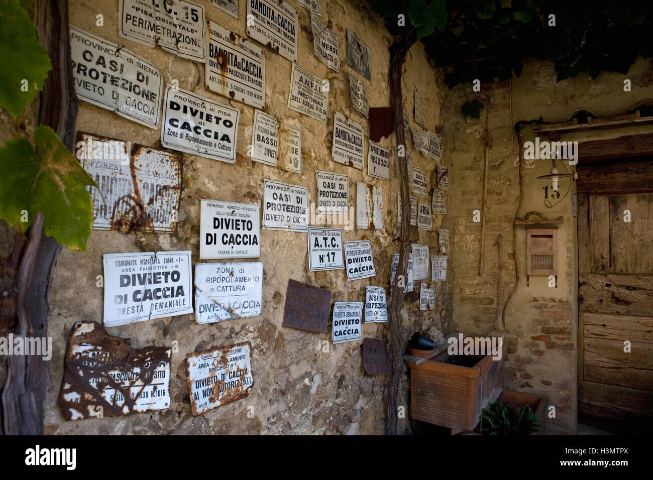 Insegne pubblicitarie un divieto di caccia la decorazione di una parete di una vecchia casa nel borgo medievale di Torri, vicino Sovicille Siena, Italia Foto Stock