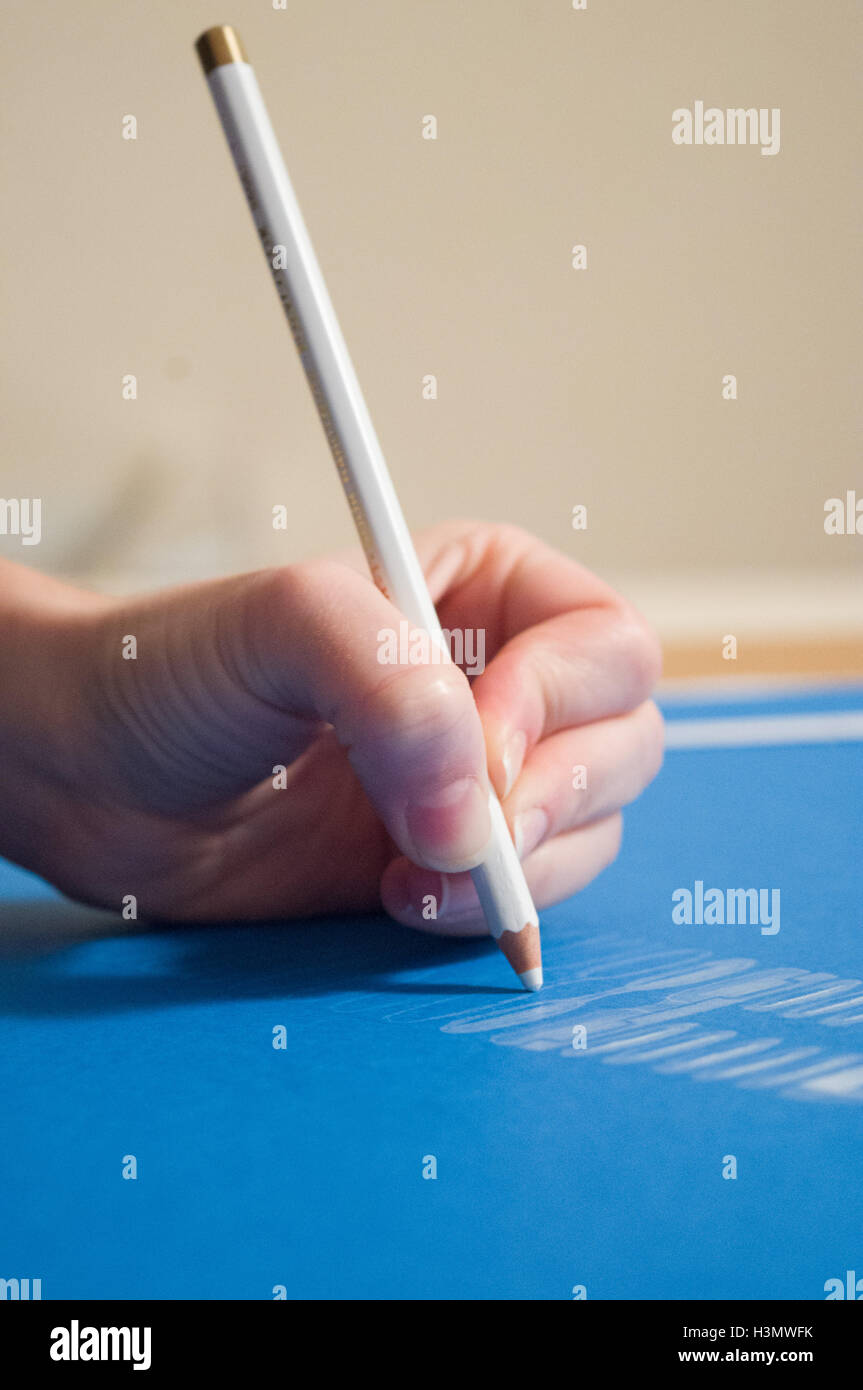 A sinistra del disegno a mano utilizzando una matita bianca su carta blu Foto Stock
