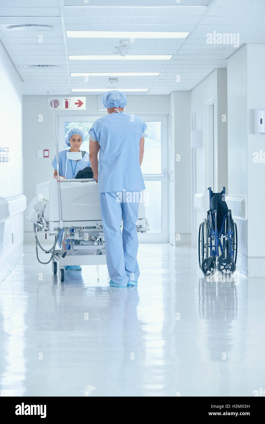 Maschio e femmina di infermieri spingendo sul letto di ospedale corridoio Foto Stock