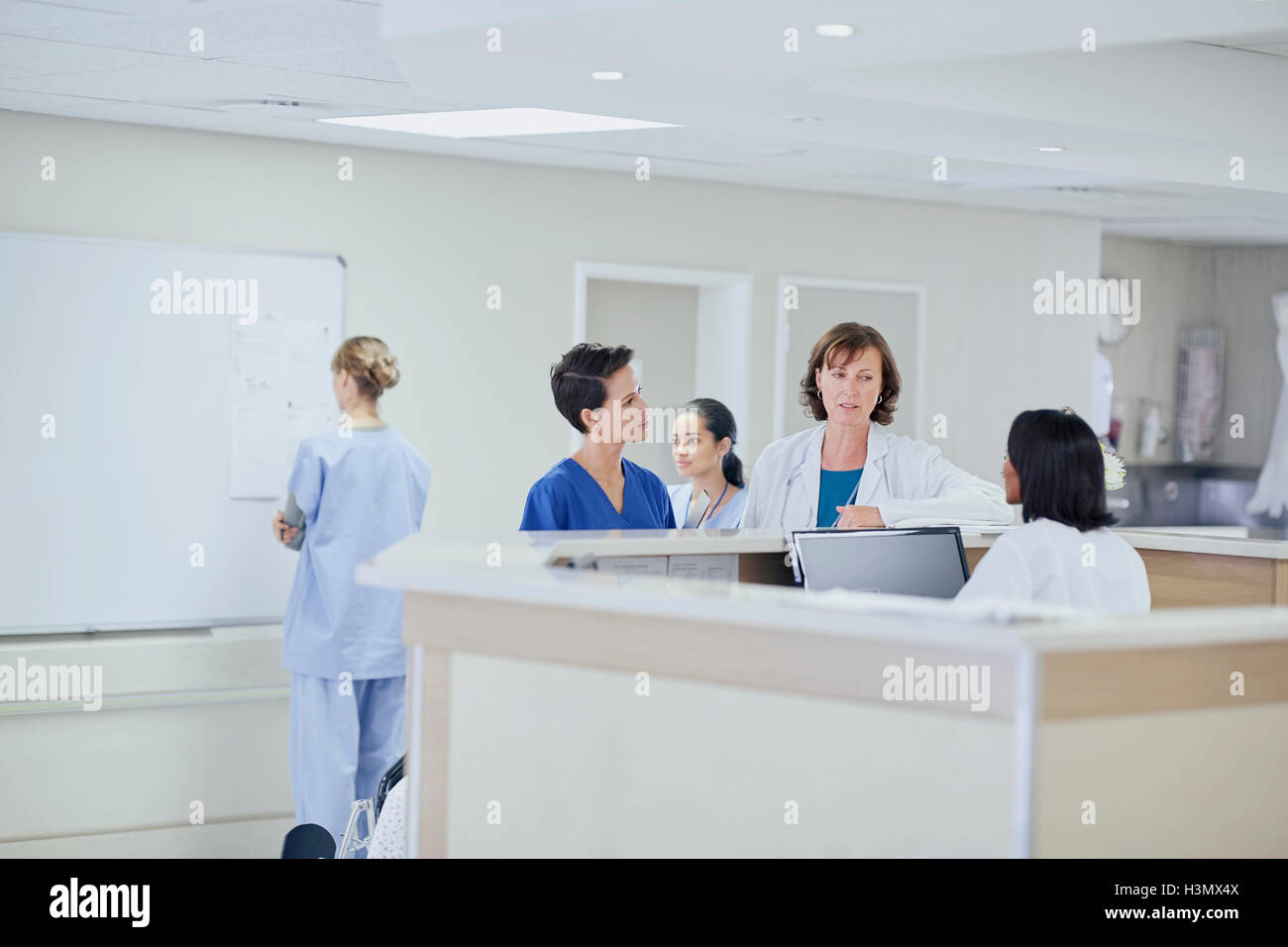 Medico donna avente la discussione con gli infermieri a stazione di infermieri in ospedale Foto Stock