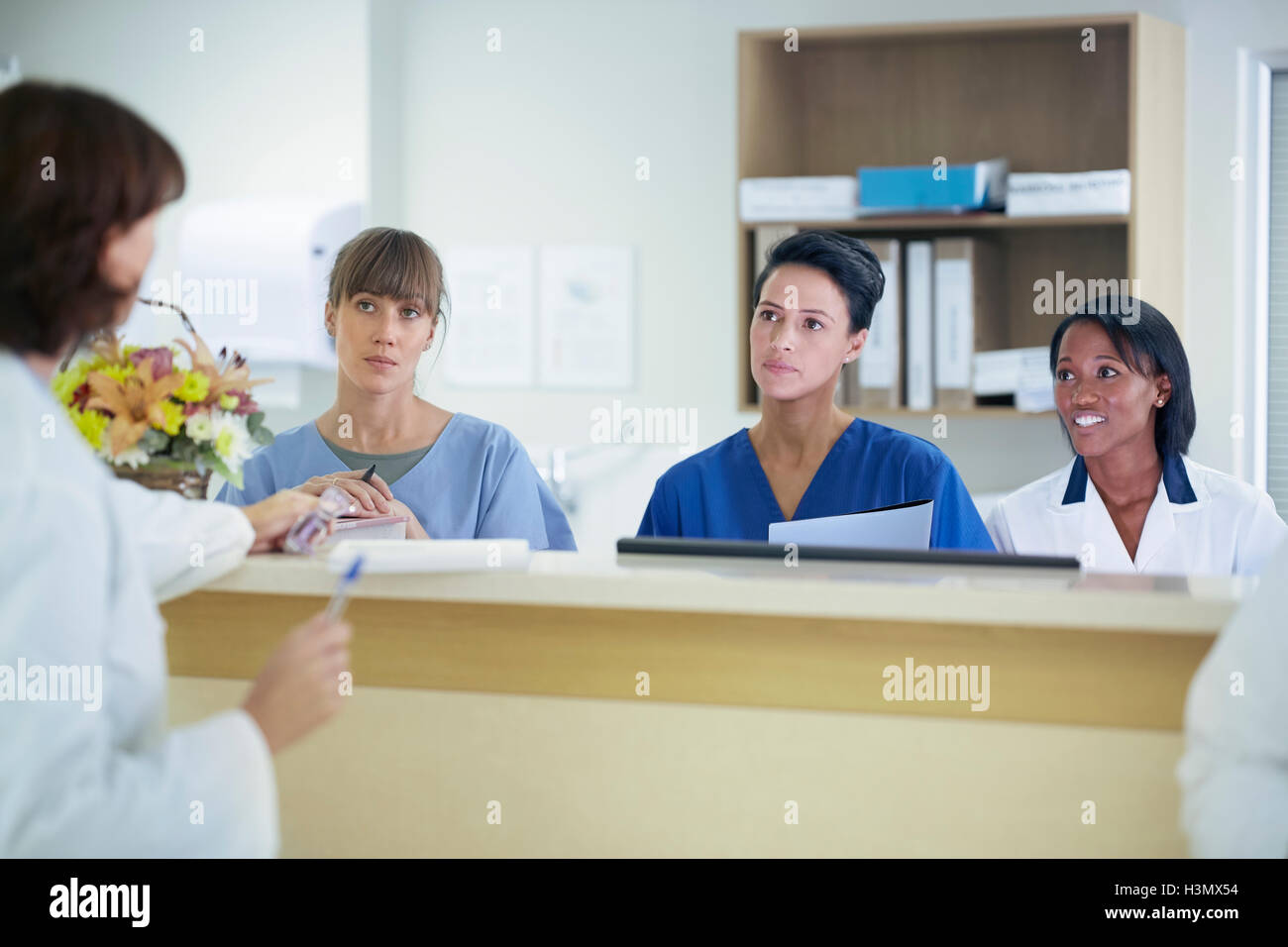 Medico donna avente la discussione con gli infermieri a stazione di infermieri in ospedale Foto Stock