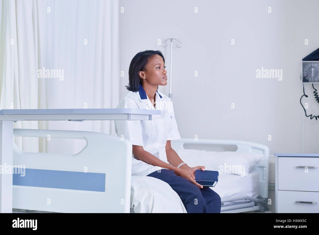 Donna seduta medic guardando dal letto di ospedale Foto Stock