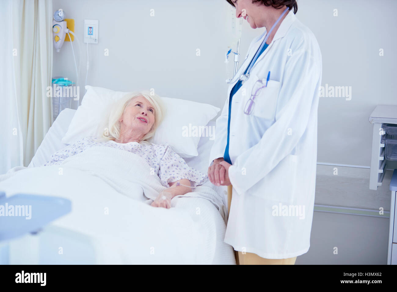Medico donna parlando di senior paziente femmina nel letto di ospedale Foto Stock