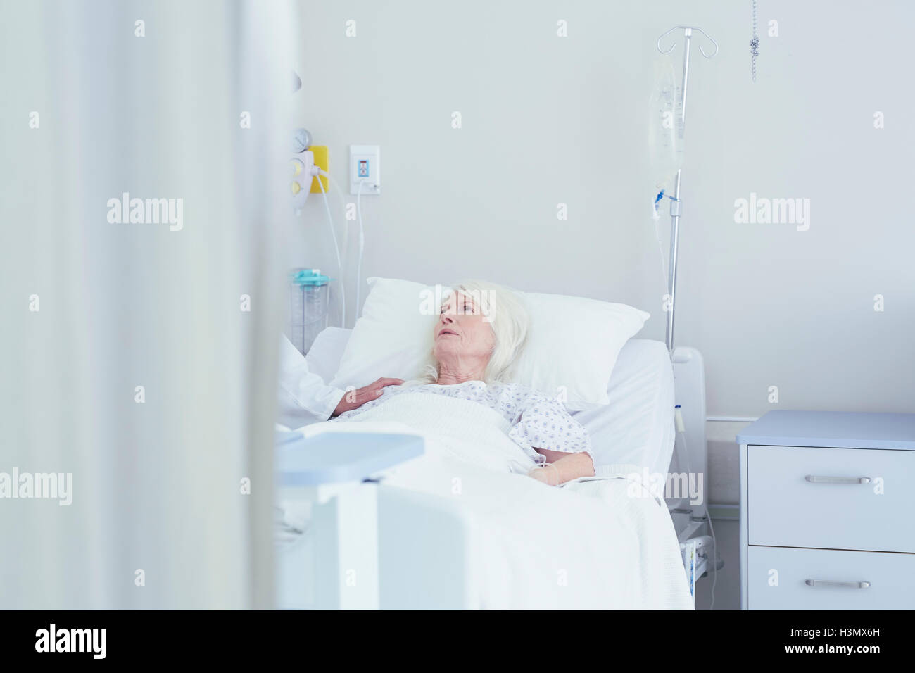 Medico parlando di preoccupato senior paziente femmina nel letto di ospedale Foto Stock