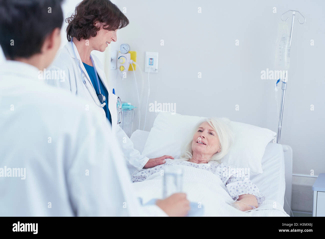 I medici a spiegare ai senior paziente femmina nel letto di ospedale Foto Stock
