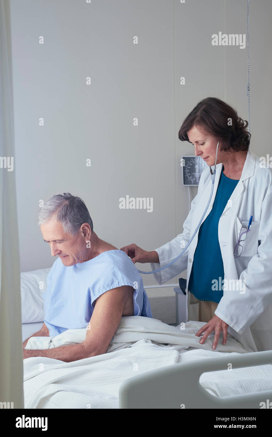 Medico donna ascolto senior paziente di sesso maschile torna con uno stetoscopio Foto Stock