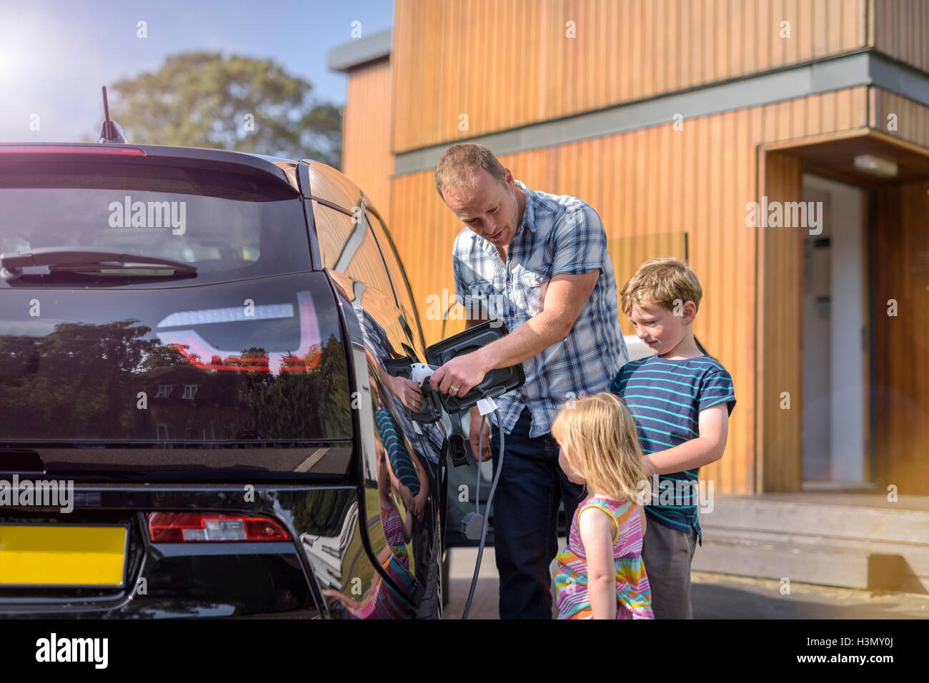 Padre con i bambini, la ricarica auto elettrica Foto Stock