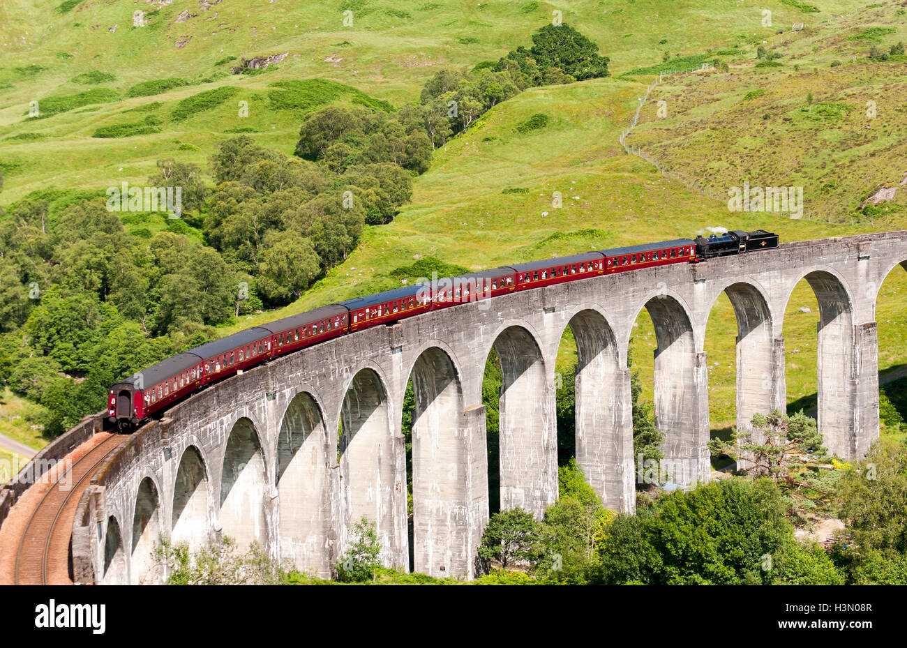 Treno a vapore sul viadotto Glenfinnan, arcuato il ponte ferroviario sul West Highland Line in Scozia, Regno Unito Foto Stock