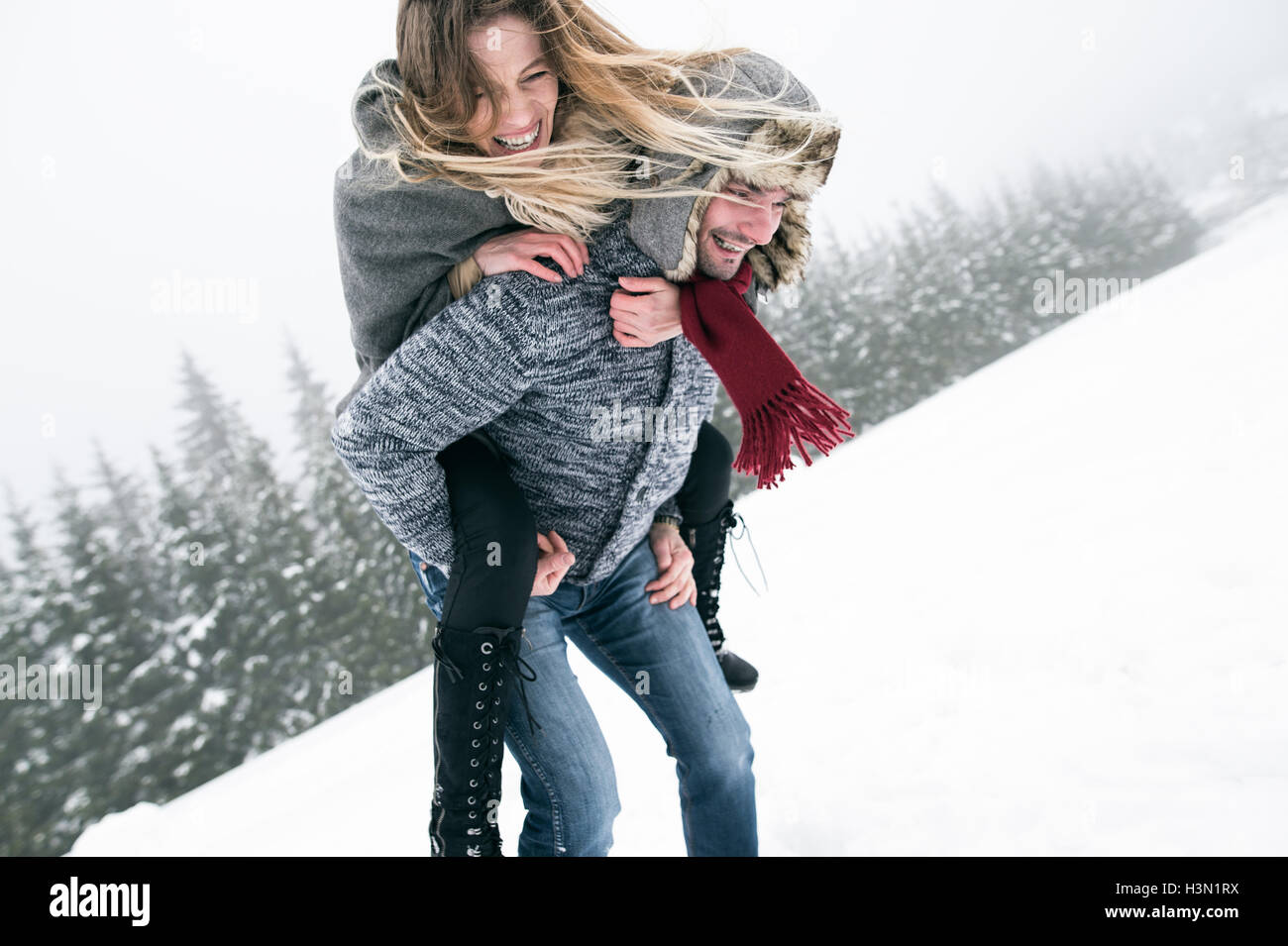 Matura in amore, dando uomo donna piggyback. Natura invernale. Foto Stock