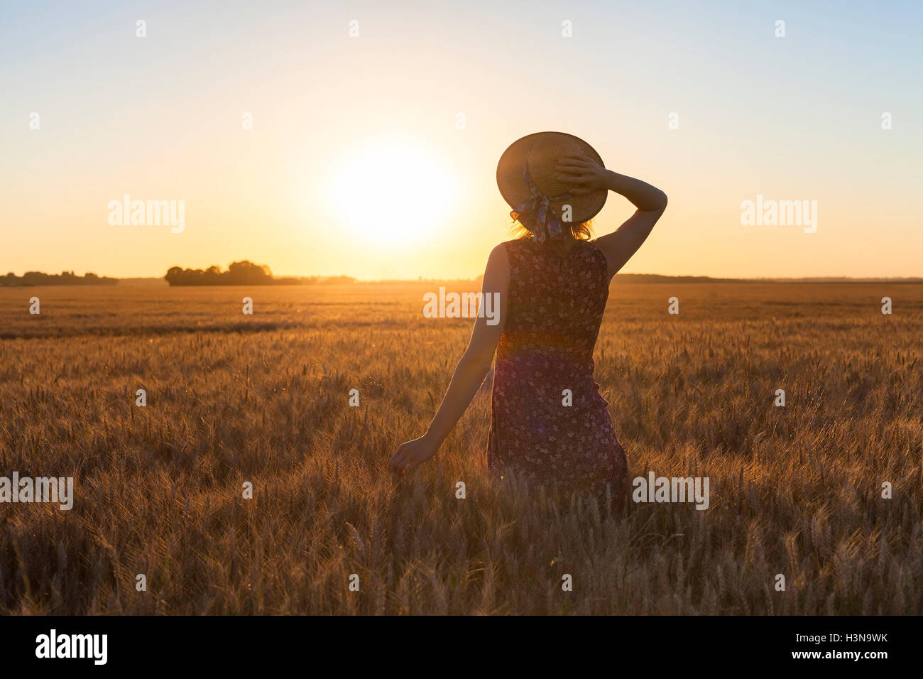 Felice ragazza godendo estate camminate nel campo al tramonto. Concetto di benessere e di vacanza sfondo Foto Stock