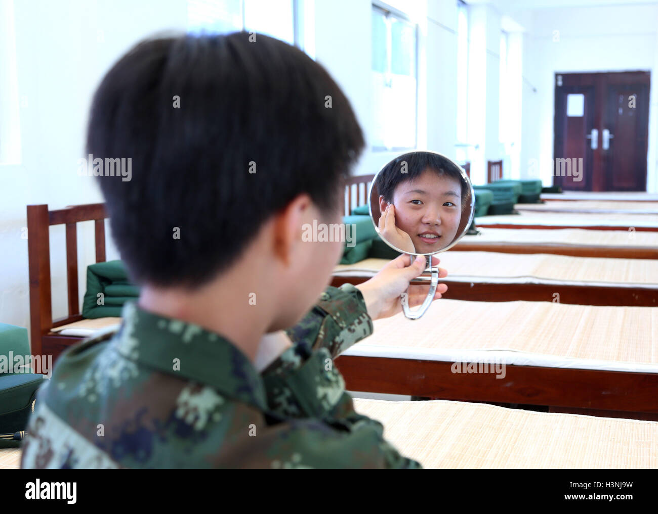 (161011) -- HAIKOU, 11 ott. 2016 (Xinhua) -- reclutare Chen Zhangjing guarda nello specchio Dongshan Training Base di Hainan Corps del popolo cinese la forza di polizia armata, Cina del sud della provincia di Hainan, 11 ott. 2016. Oltre 20 donne nuove reclute sono state prendendo per tre mesi un sessione di allenamento nella base. (Xinhua/Le Zhe) (wx) Foto Stock