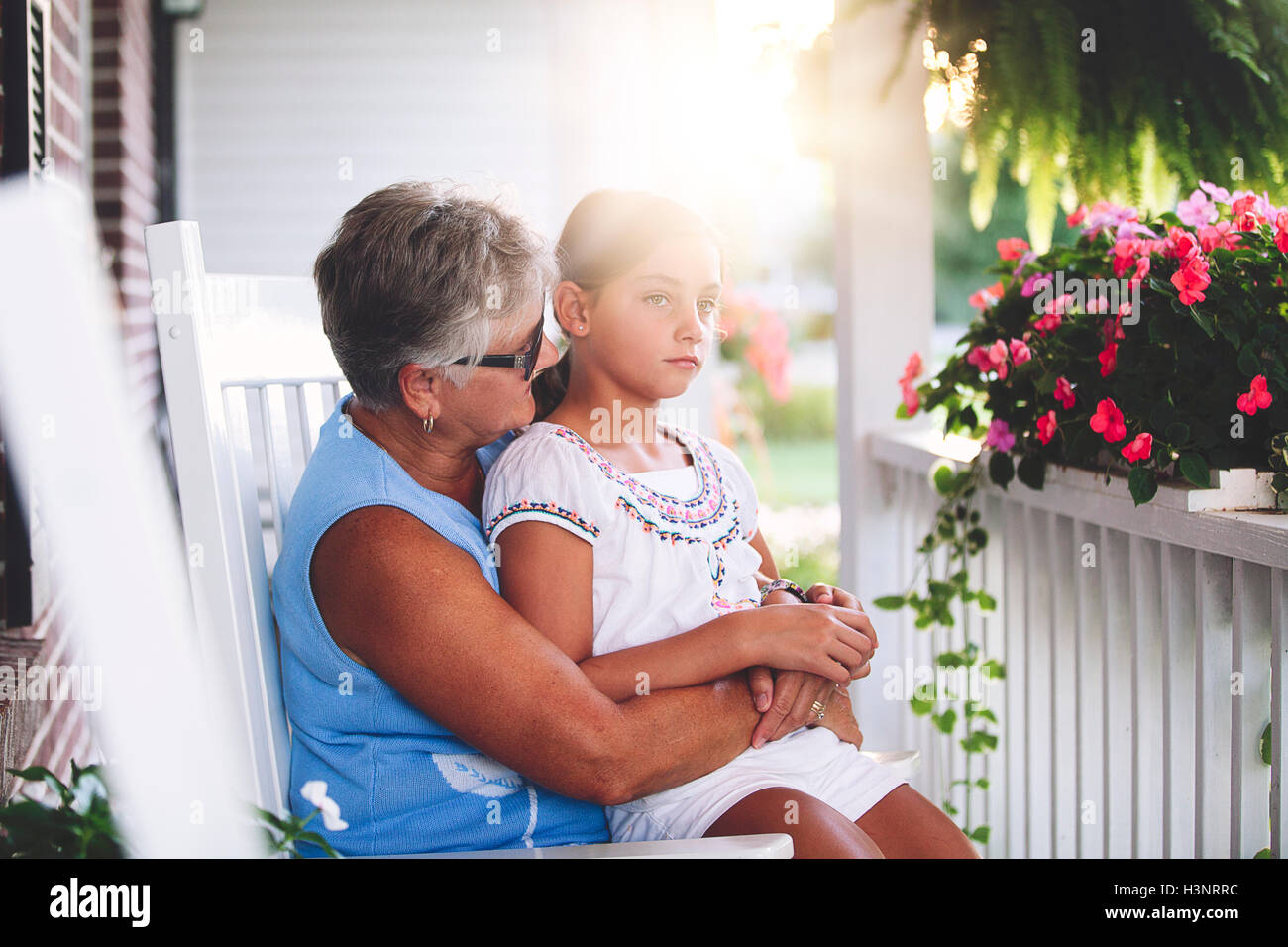 Ragazza seduta su alla nonna giro in veranda al tramonto Foto Stock