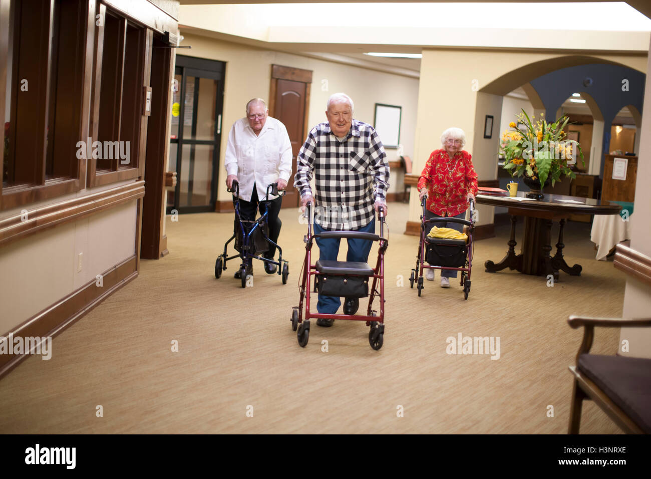 Tre adulti senior camminare in luoghi chiusi con telai a piedi Foto Stock