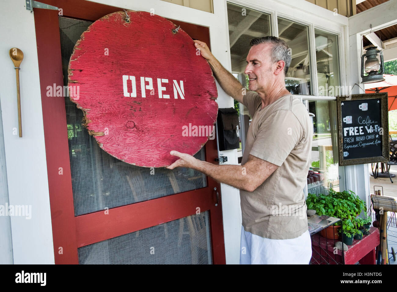 Cafe proprietario mettendo su digital signage su porta anteriore Foto Stock