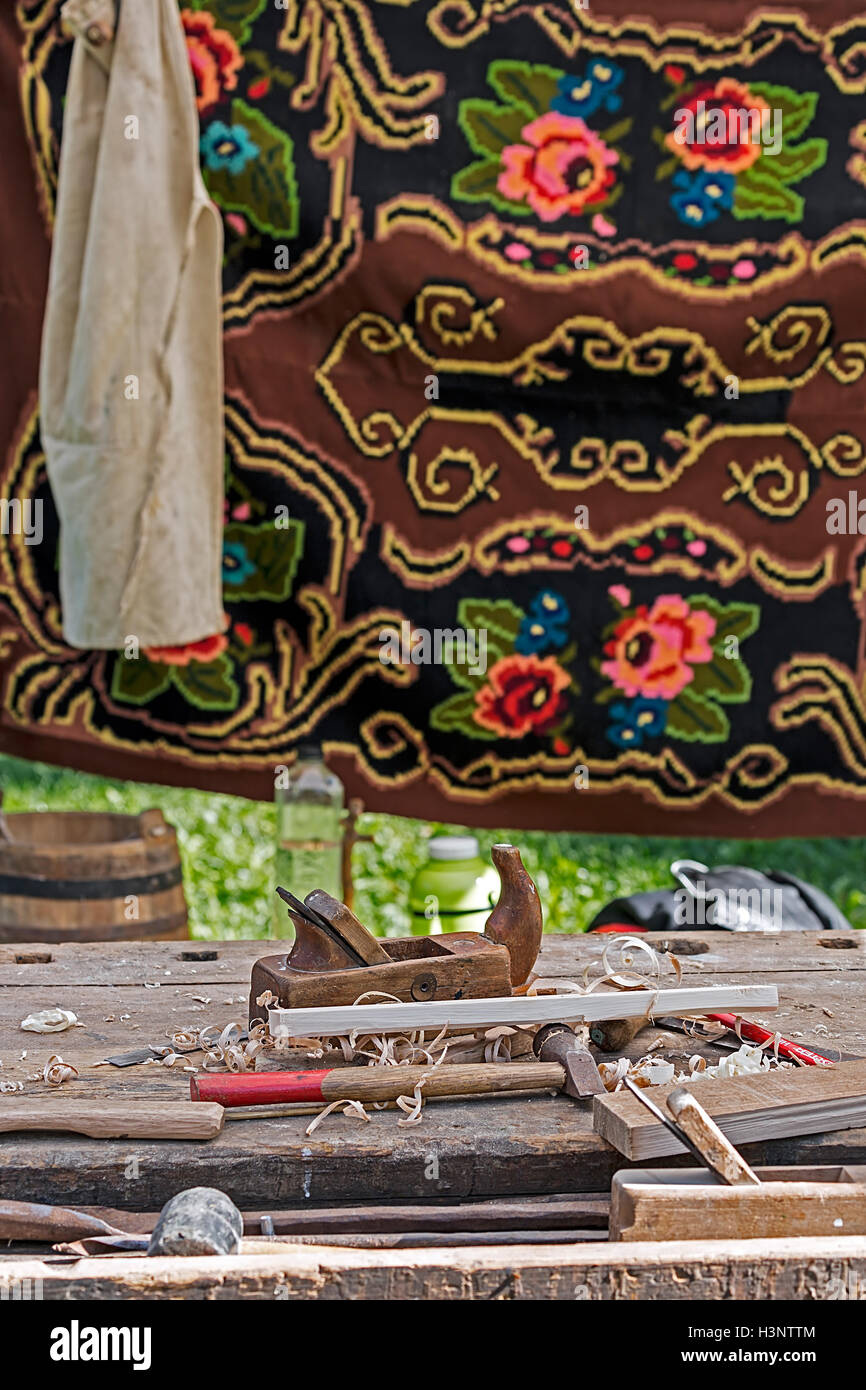 Gli strumenti tradizionali per la lavorazione del legno e di un rumeno specifico materiale di sfondo con ricamo. Foto Stock