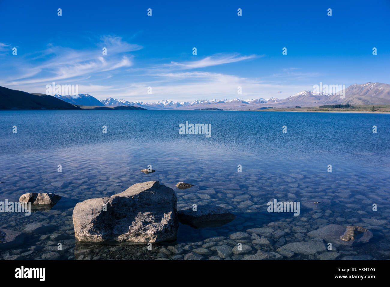 Panorama del lago con rock in avanti la massa e la gamma della montagna in background Foto Stock