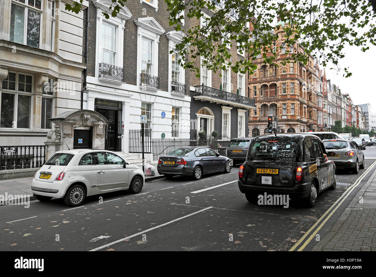 Una vista di nero con taxi nel traffico di Harley Street W1G in autunno a West London Inghilterra England Regno Unito KATHY DEWITT Foto Stock