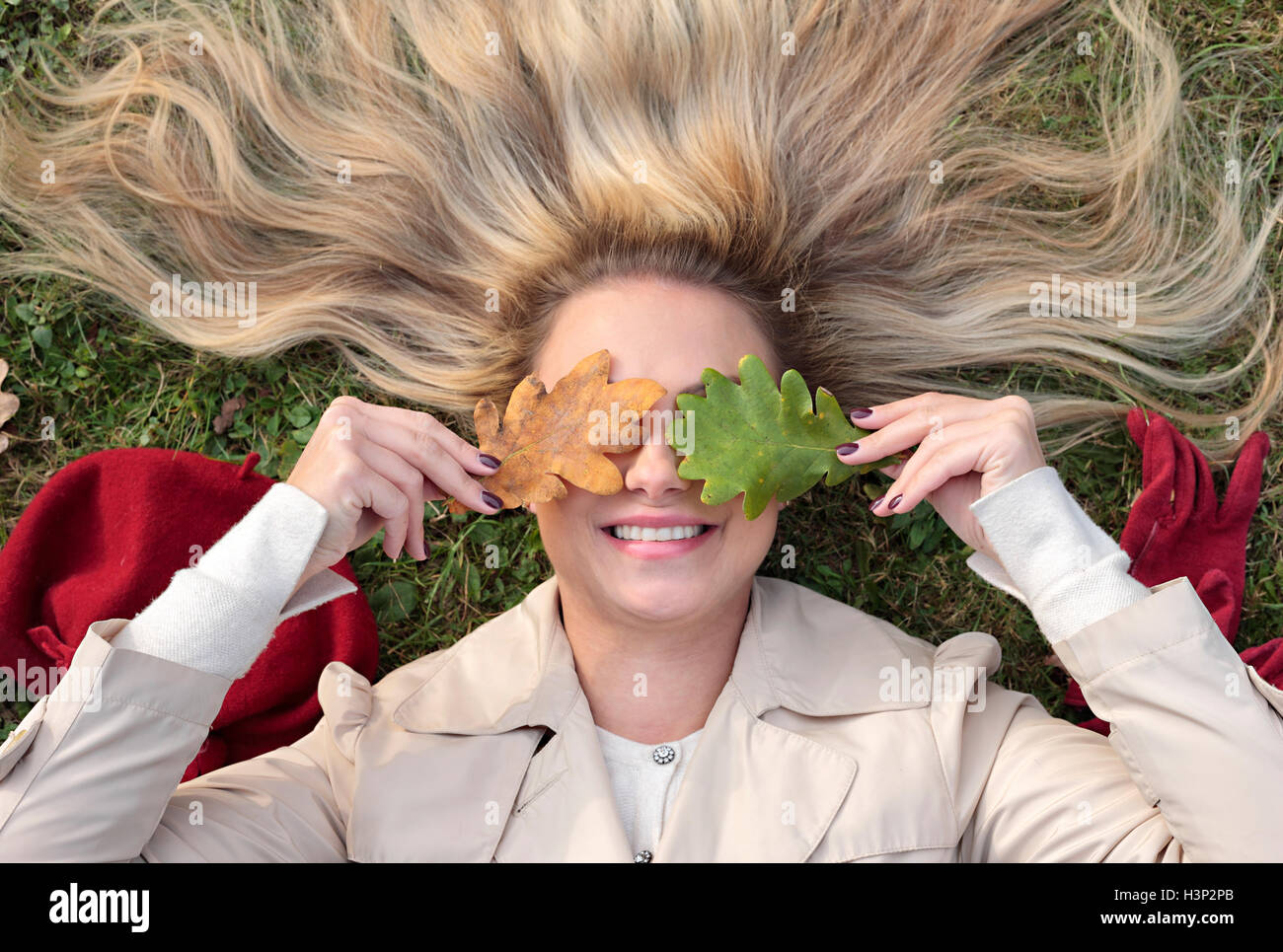 Donna sdraiata su un prato con gli occhi coperti con foglie Foto Stock