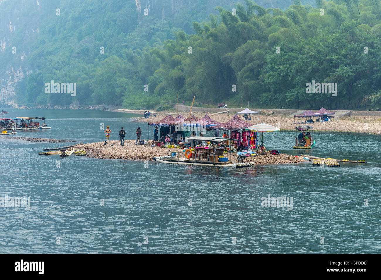 Persone, luoghi di mercato e zattere di bambù su una piccola isola sul fiume Li in Yangshuo, Guangxi, Cina Foto Stock